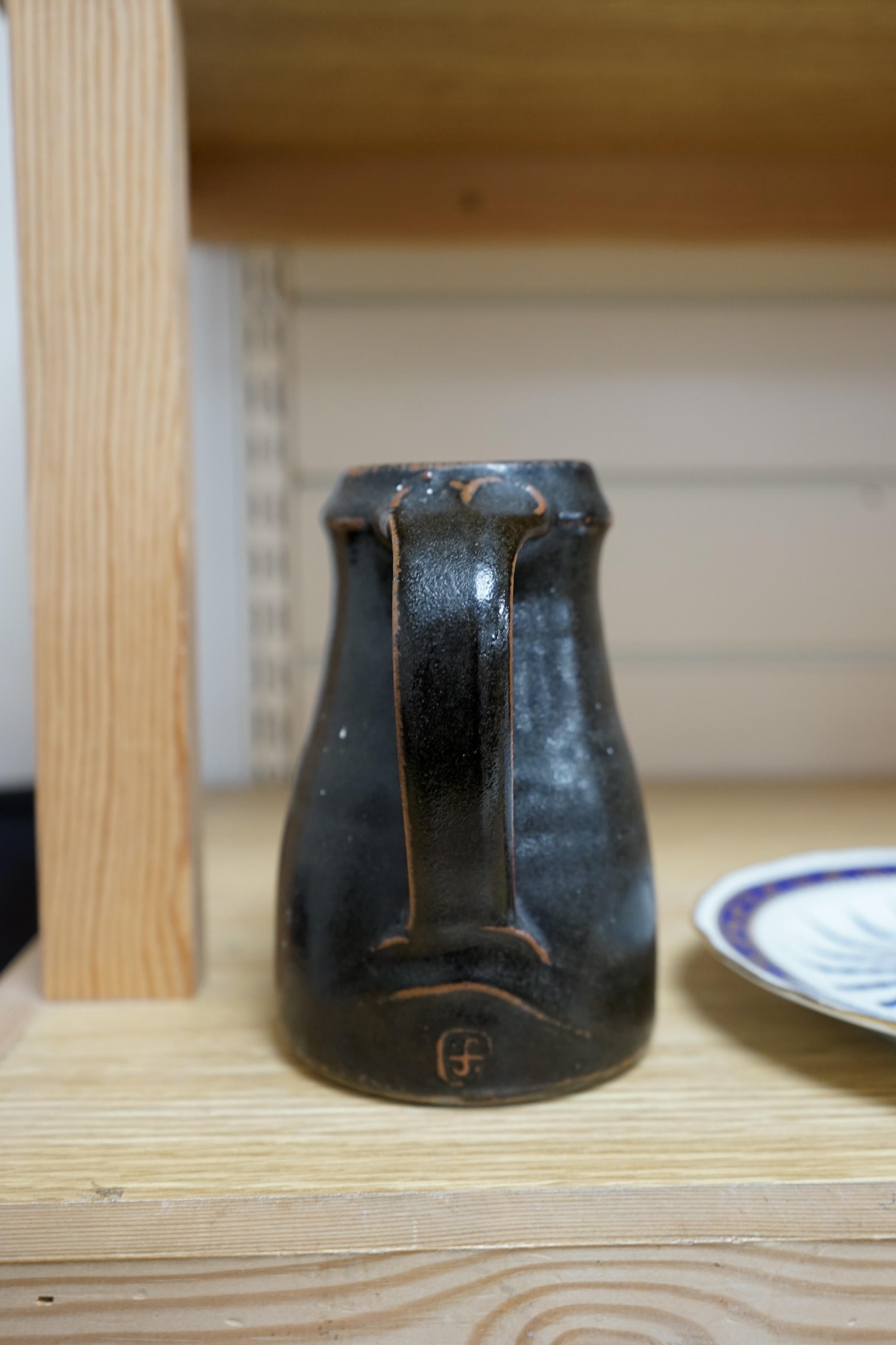 Leach standard ware, a small Stoneware black glazed studio pottery jug, impressed mark to top of foot rim, 15.5cm high. Condition - good